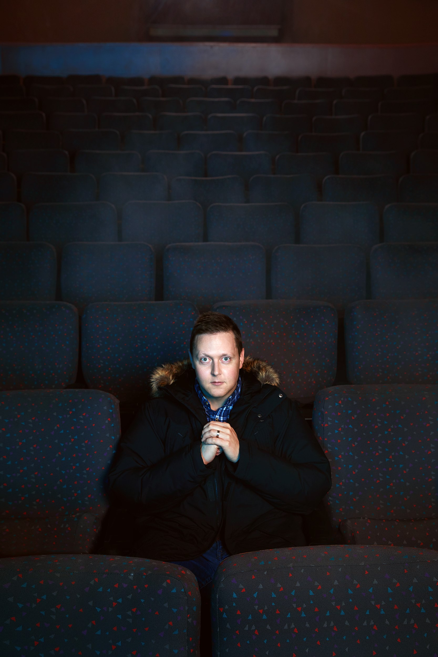Seated square to the camera in a parka, hands together