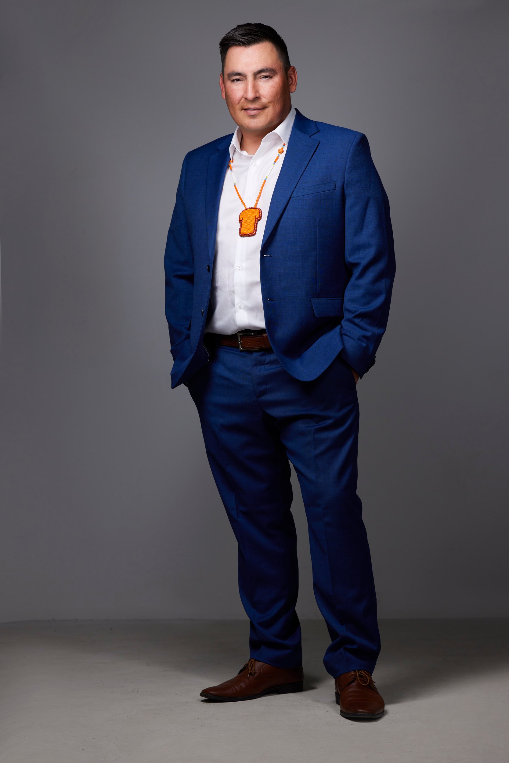Leadership portrait: a blue suit and an orange pendant, full length