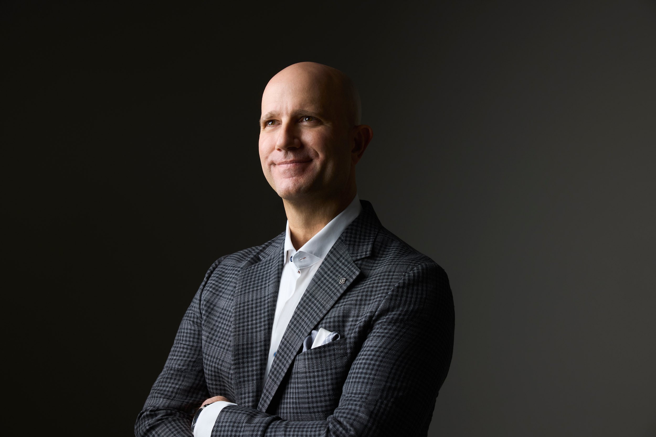 The same session: a grey check jacket, arms crossed, lit from the side