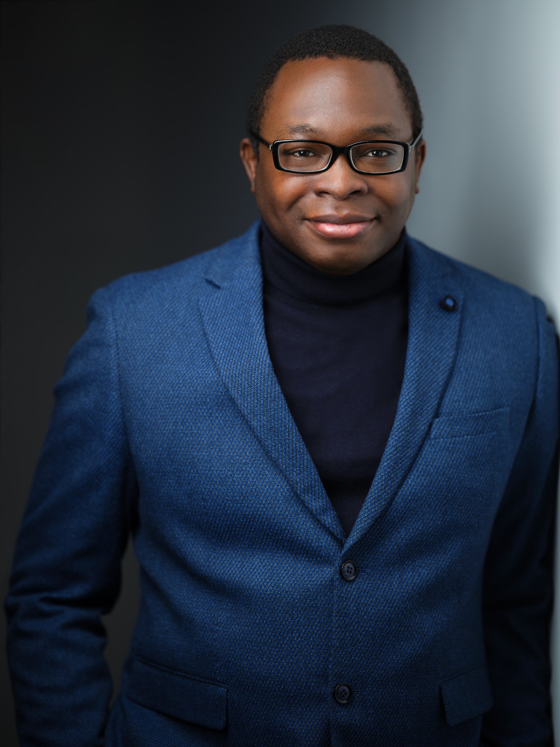 The same session: a blue blazer, seated against a wall of light