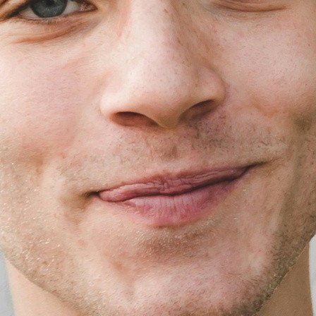 Real photo: a close-up of a young man’s mouth and chin, with light, patchy stubble