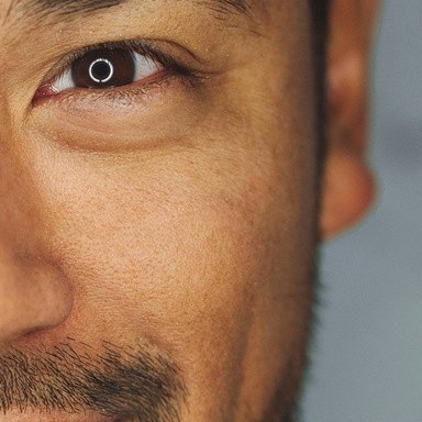 Real photo: a close-up of a smiling man’s eye and cheek