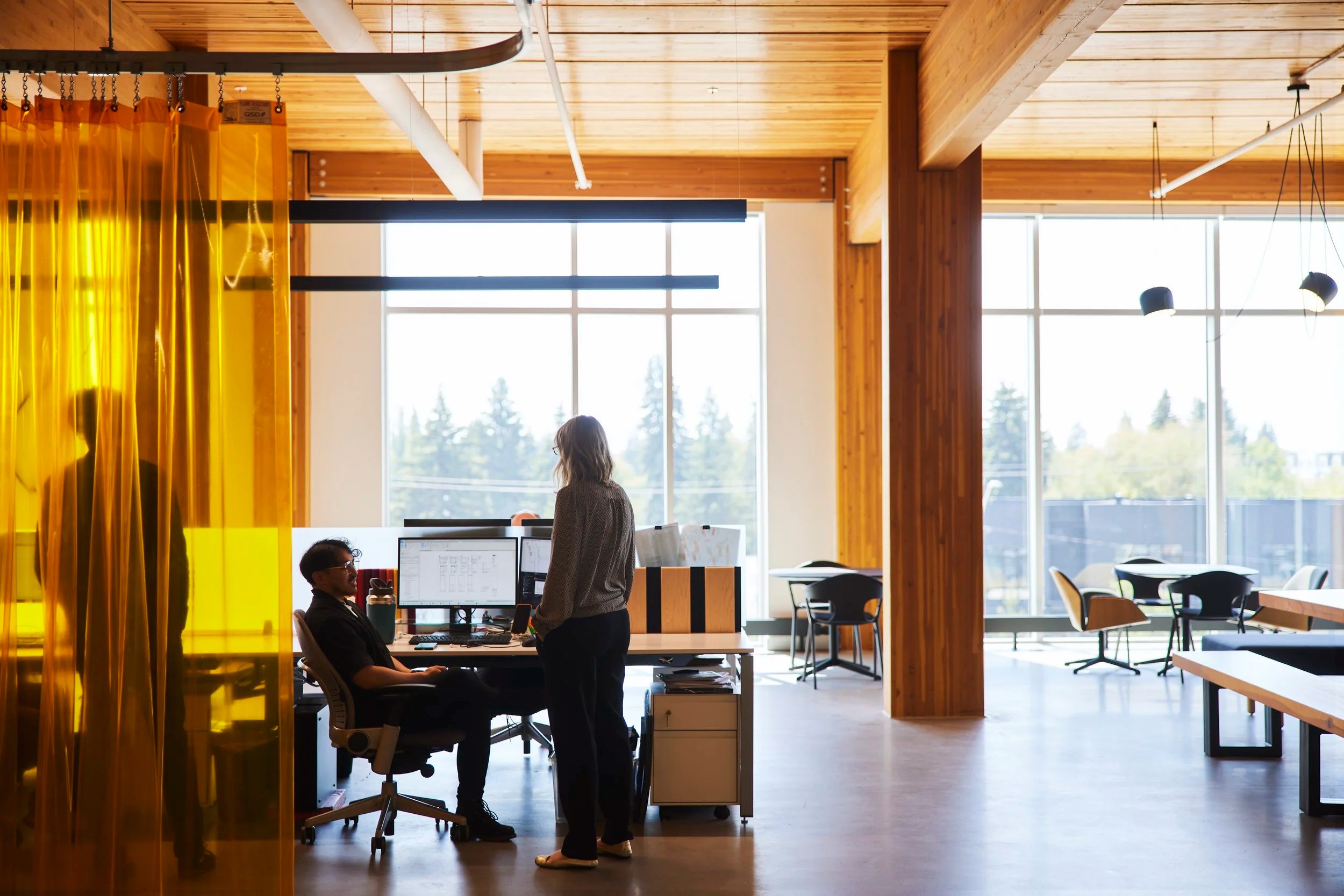 Two colleagues at a desk behind an orange glass partition