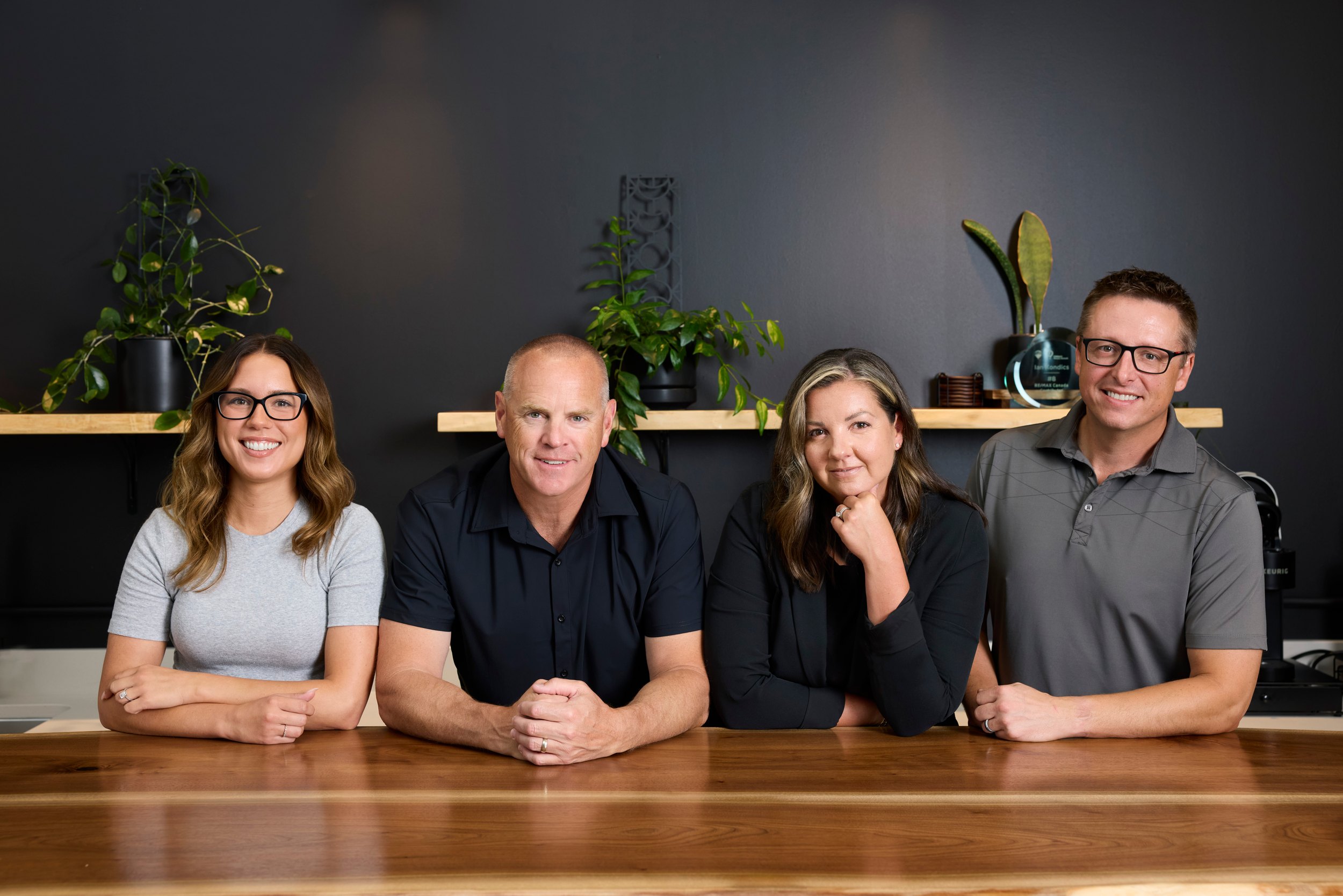 Group photo of a four-person team at a table in their own office, Edmonton