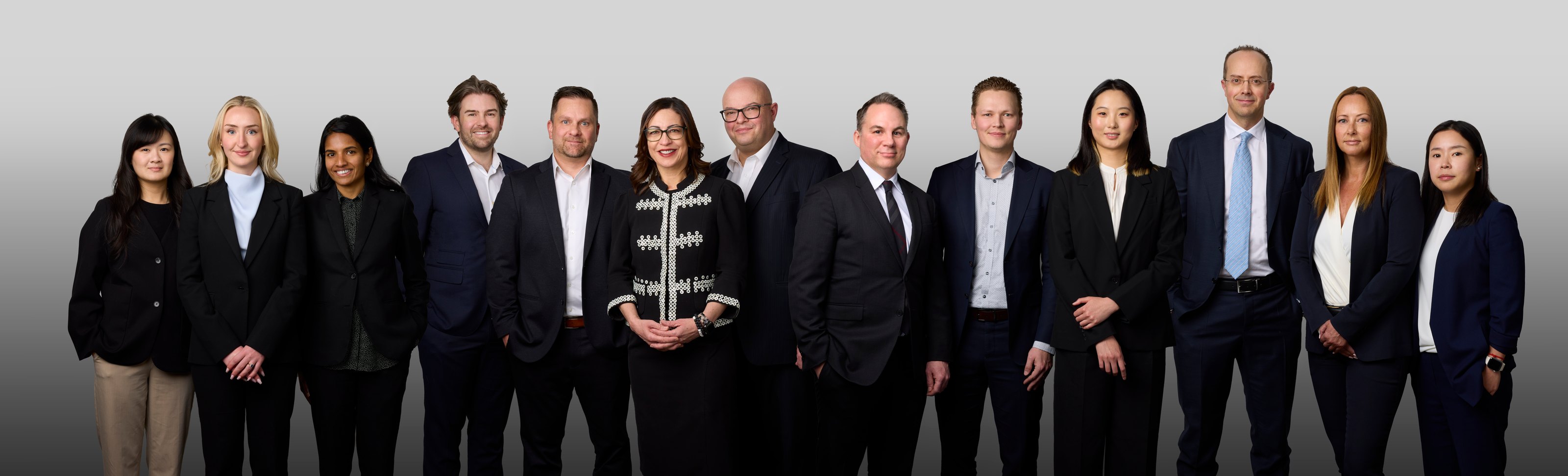 Group photo of a thirteen-person team on white, built one portrait at a time