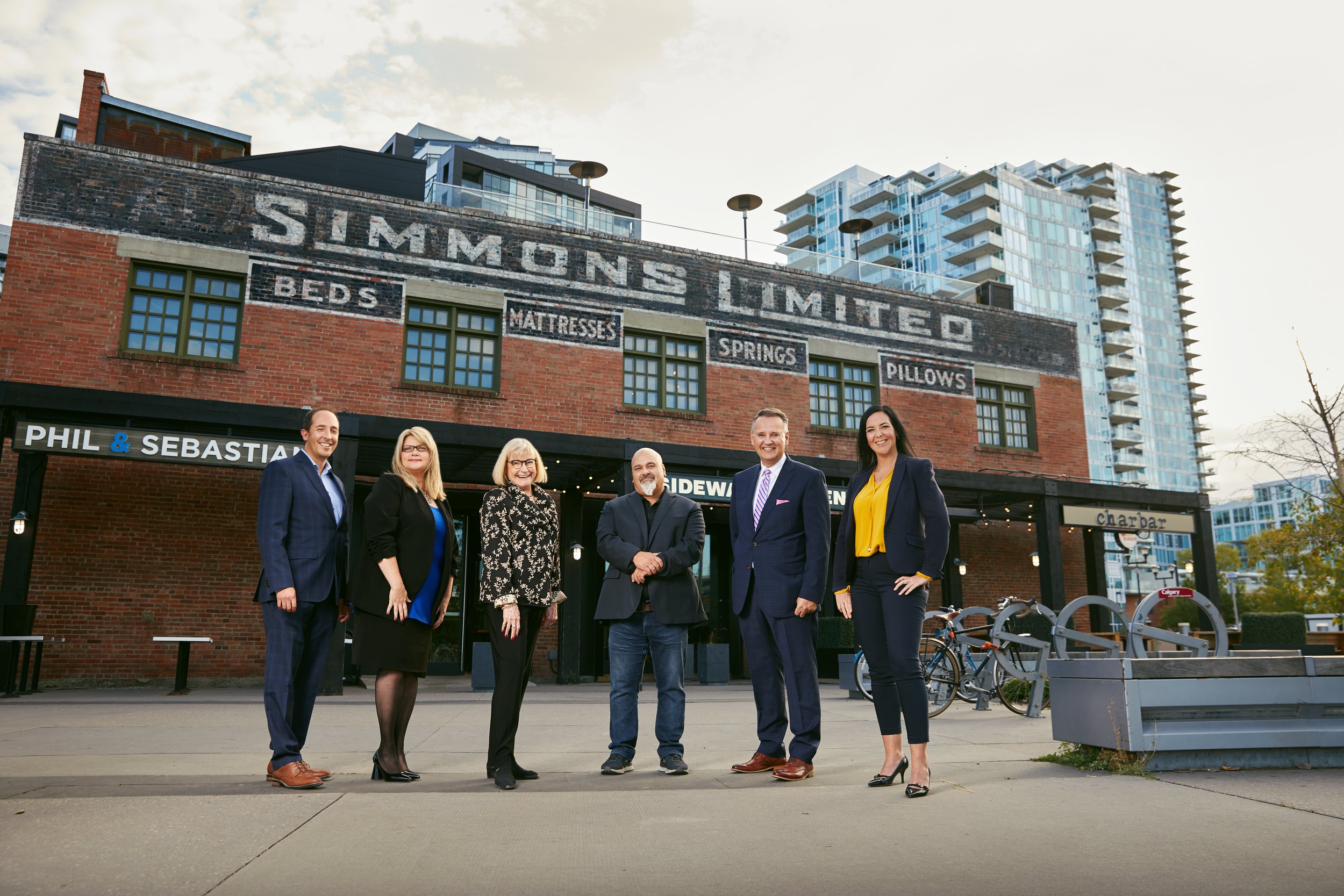 Group photo of a six-person team outside a brick building, Edmonton