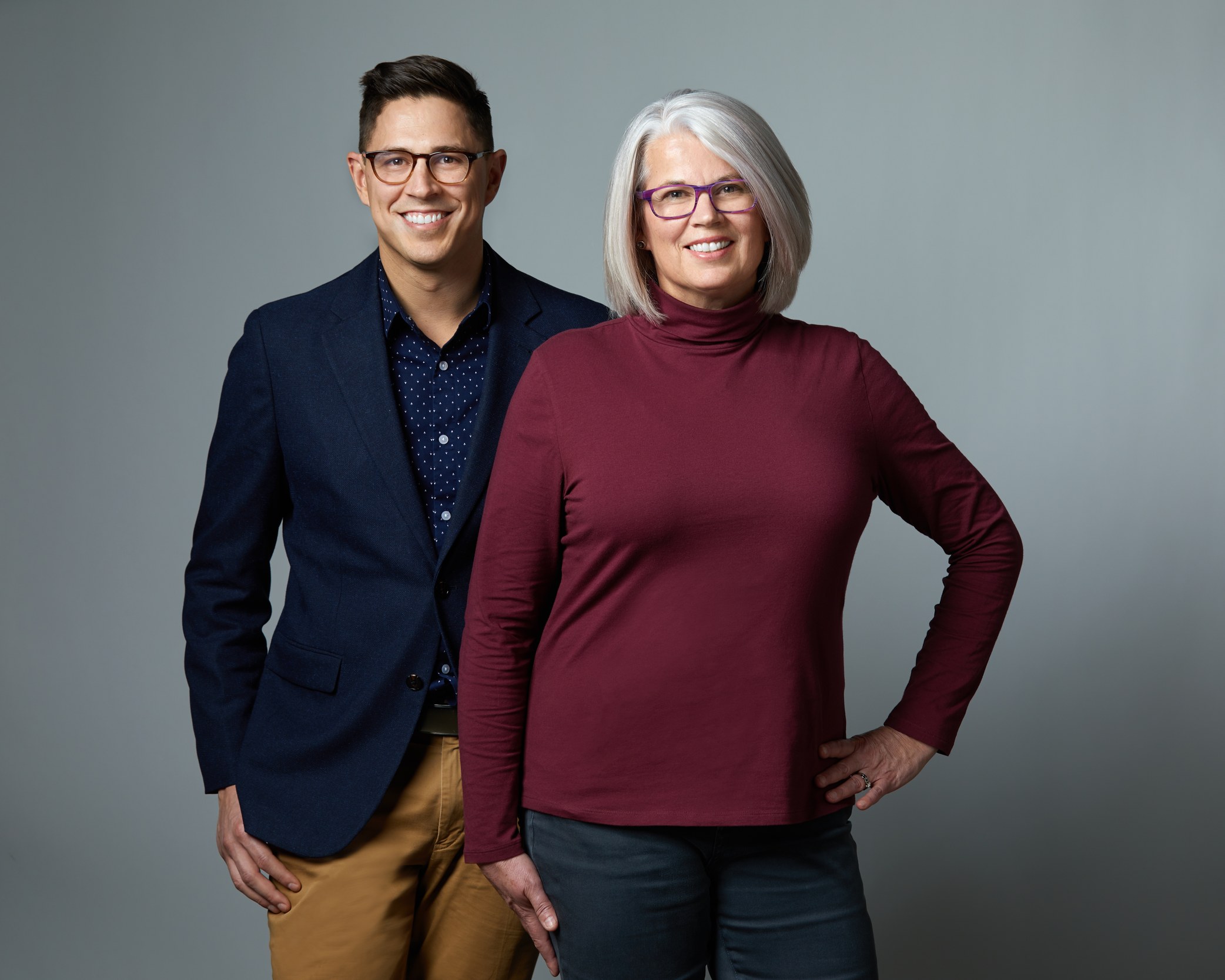 Two colleagues on grey, one in a navy blazer and one in burgundy, Edmonton studio