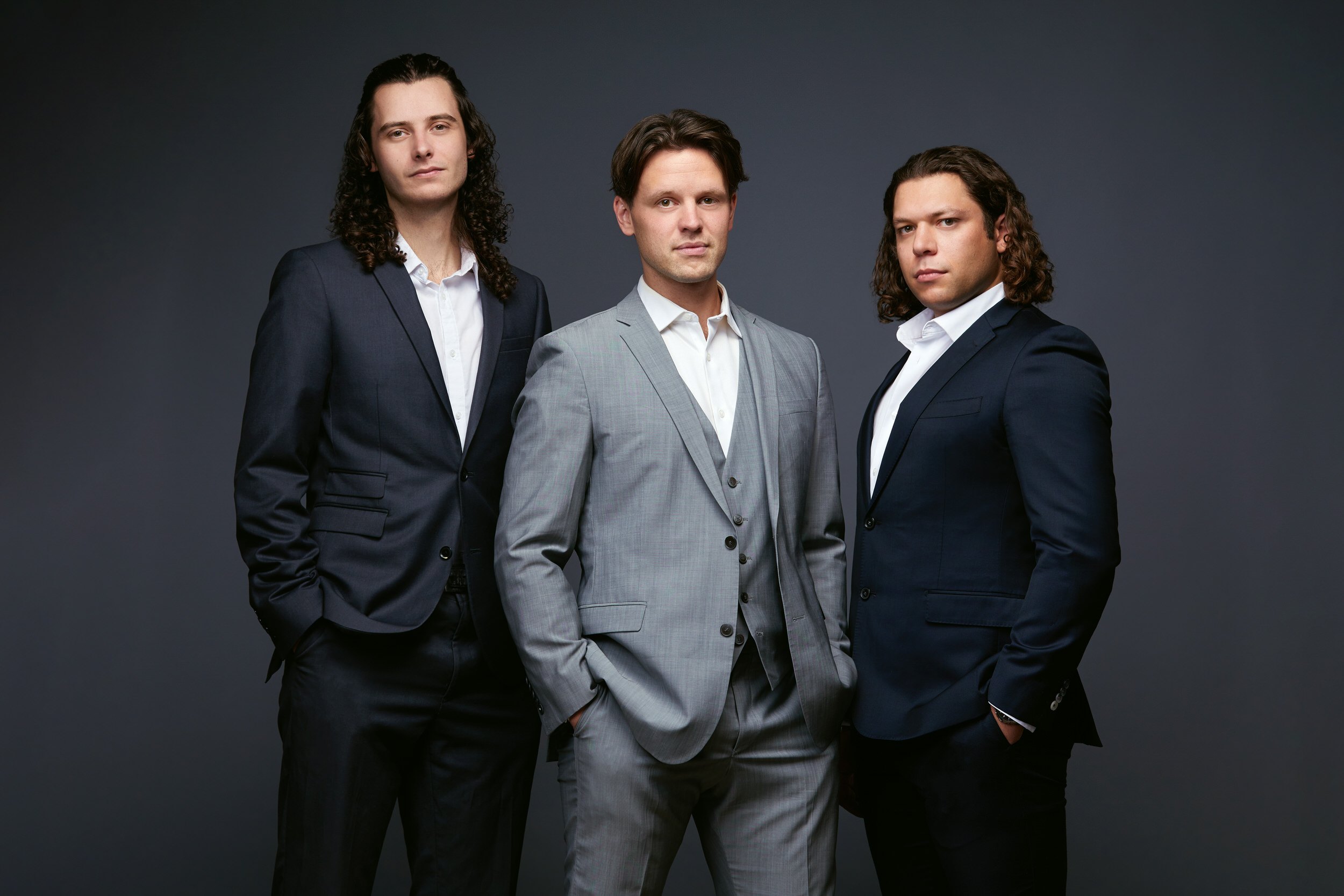 Group photo of three men in suits on grey, Edmonton studio