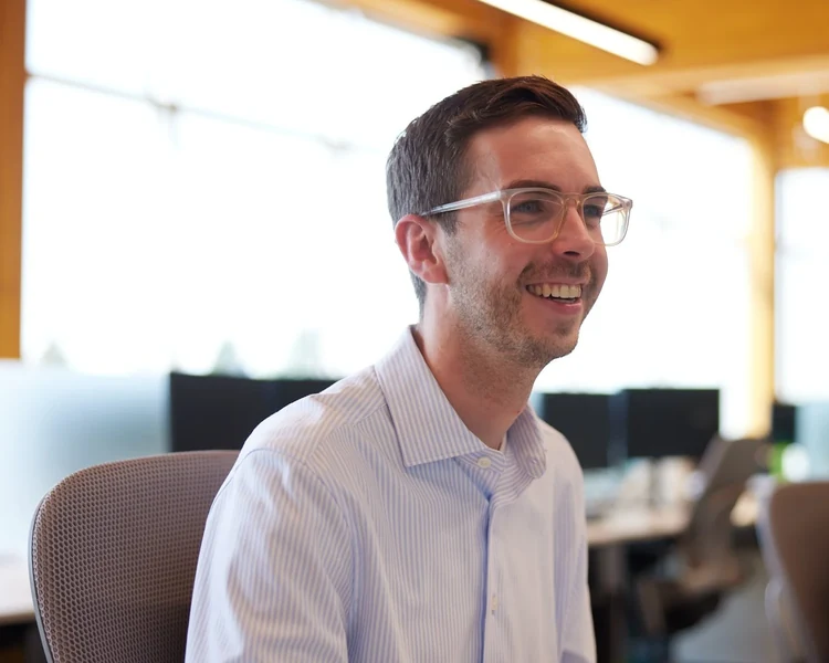 A man in glasses smiling at his monitor