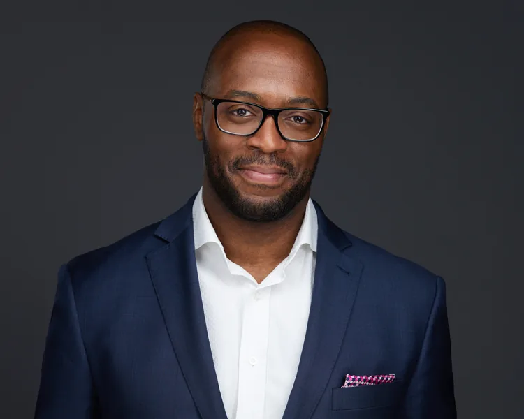 A tight corporate headshot, navy jacket on dark grey