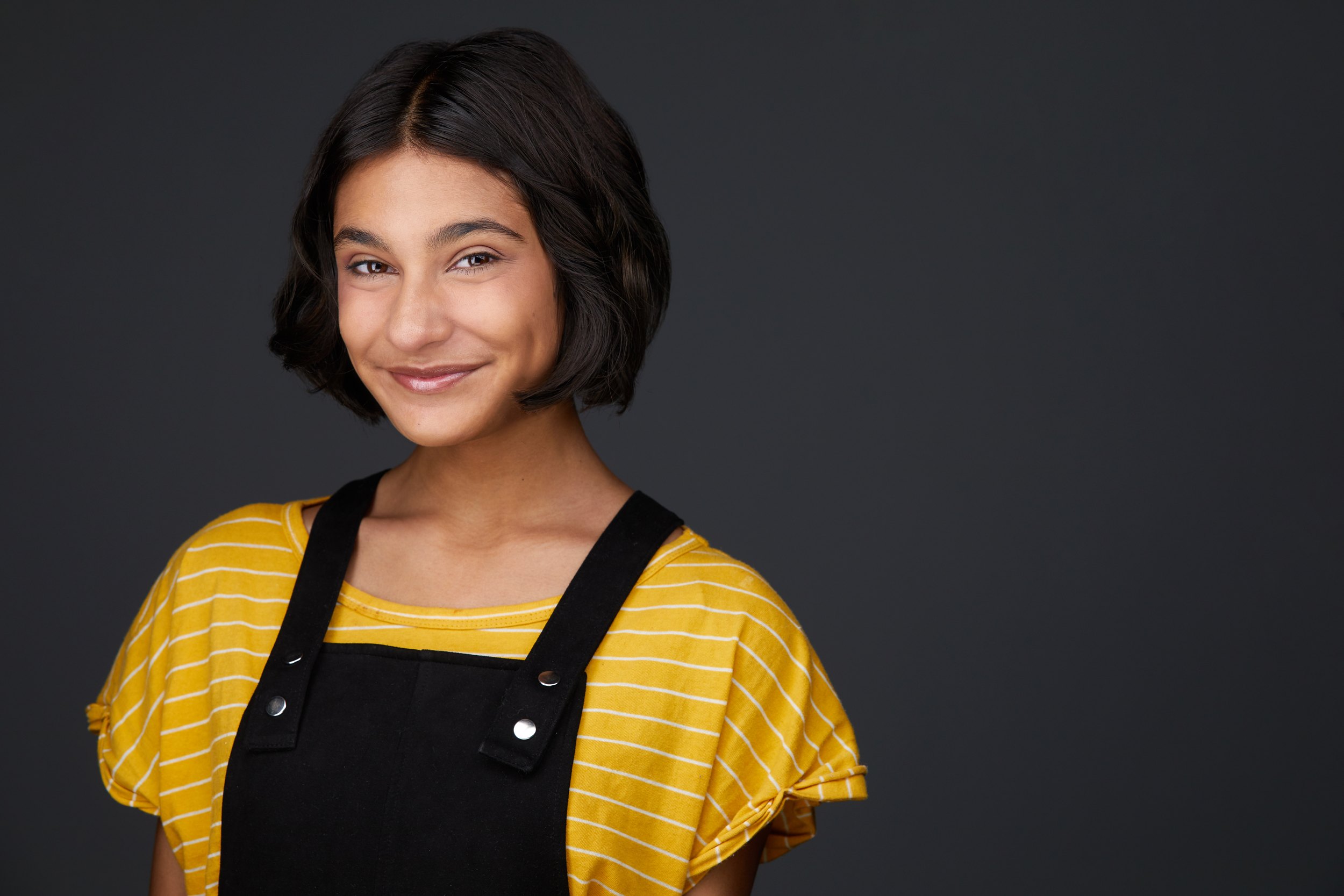 The same session, a yellow top under black overalls against grey
