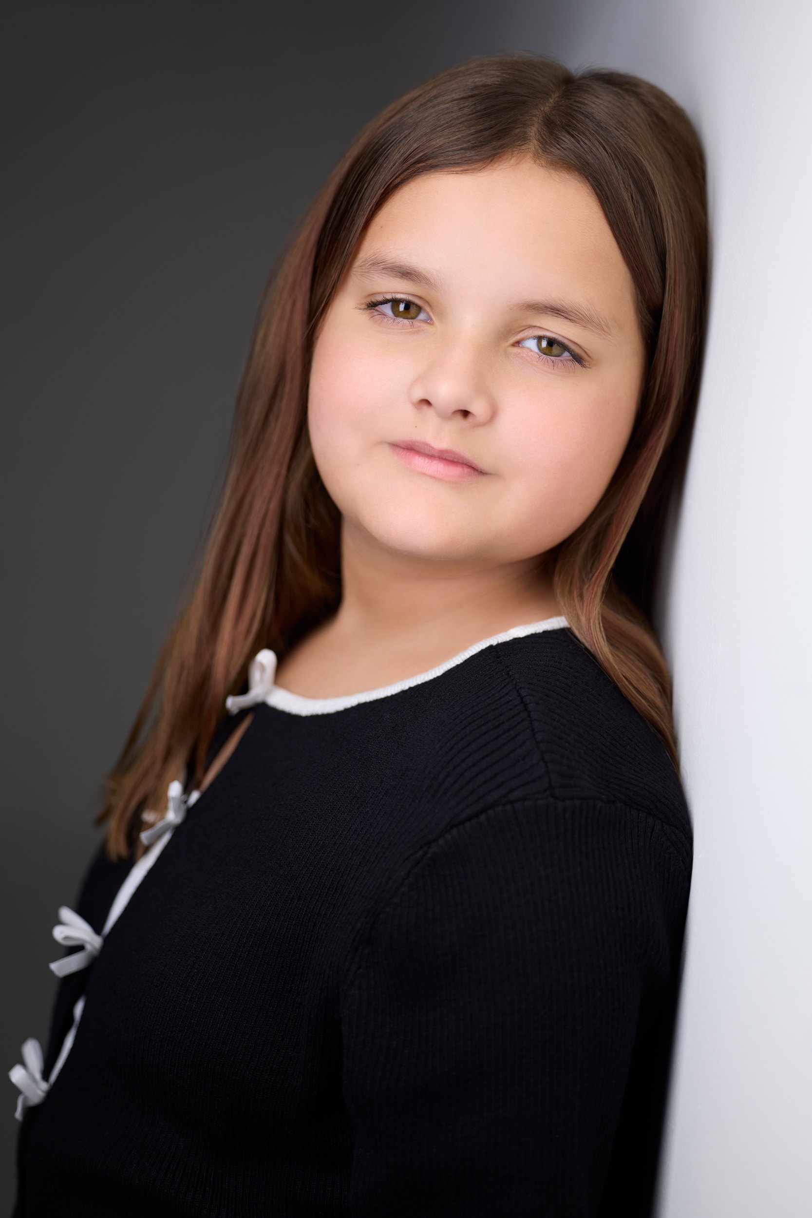 The same session, a black sweater with white bows against the wall of light