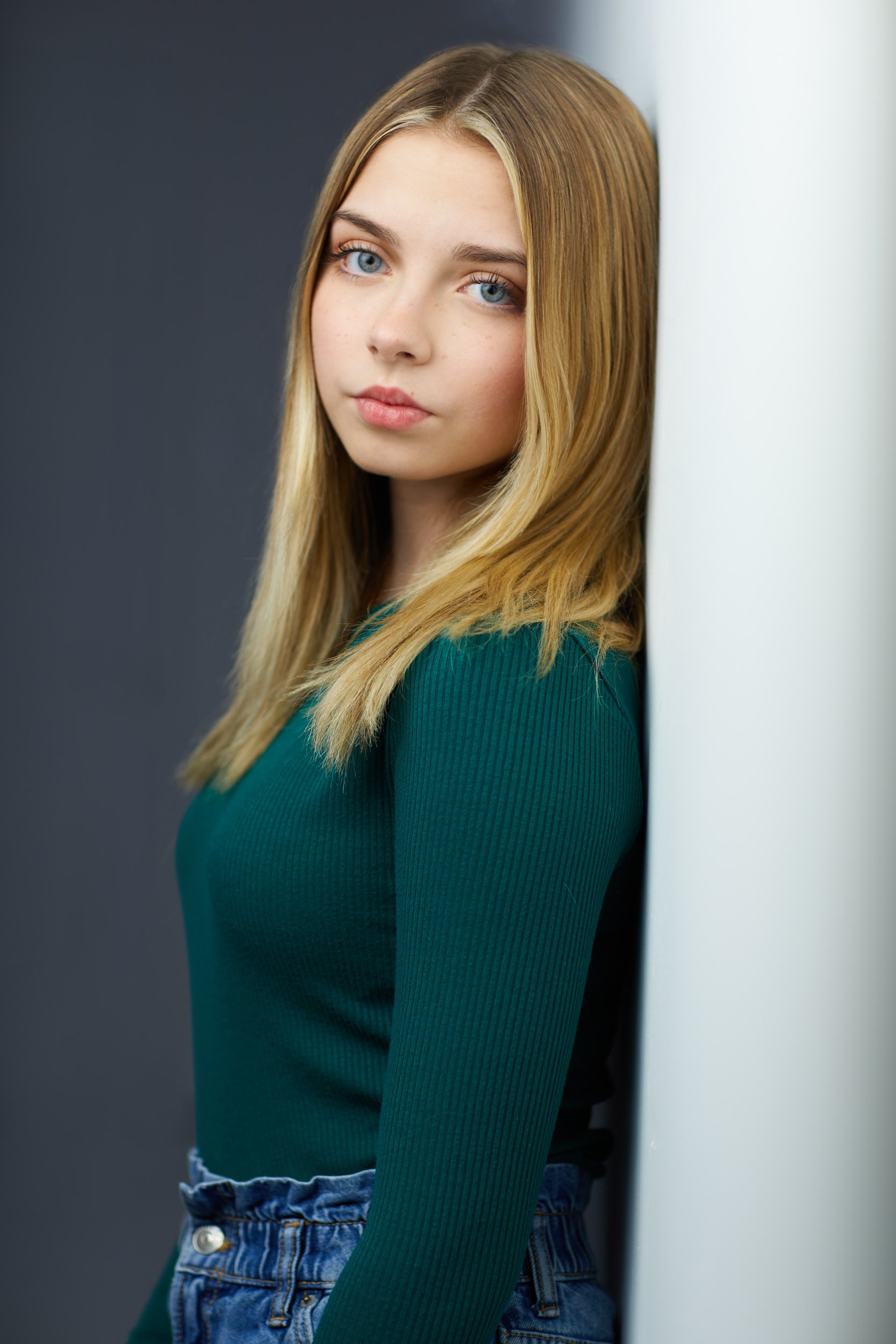 Kids and teens headshot: a green top and jeans against the wall of light