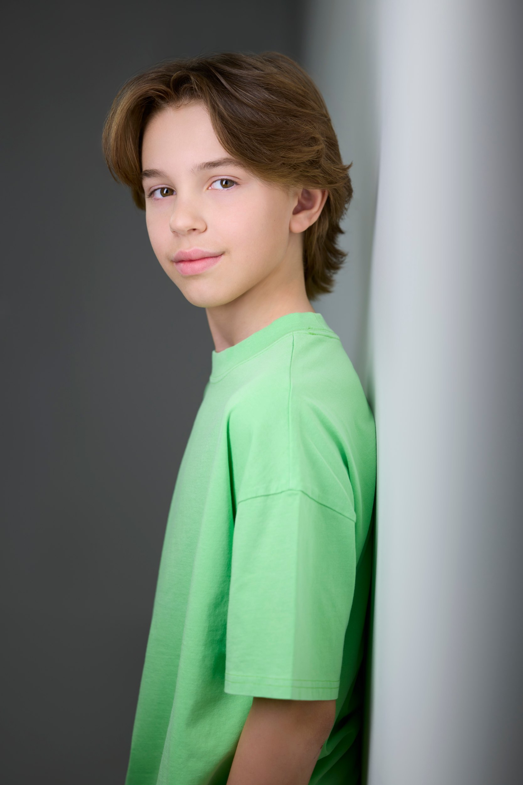 Kids and teens headshot: a green tee against the wall of light, turned