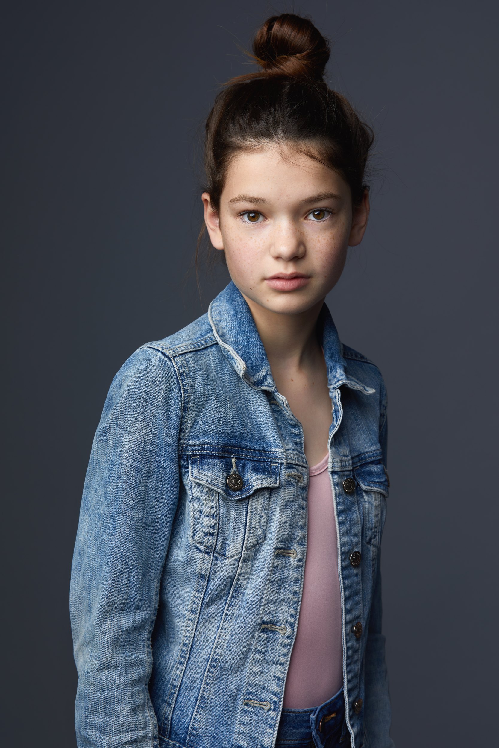 Kids and teens headshot: a denim jacket over pink against grey, hair up