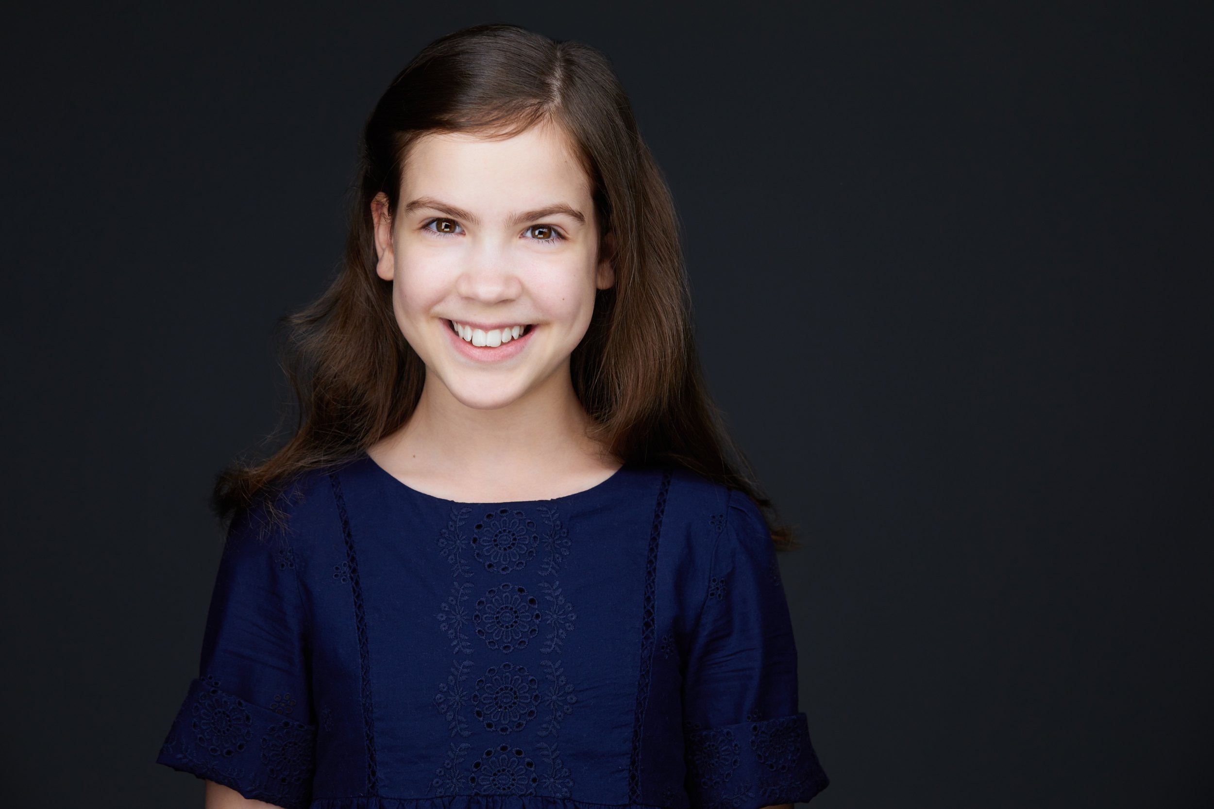 Kids and teens headshot: a navy top against grey, smiling
