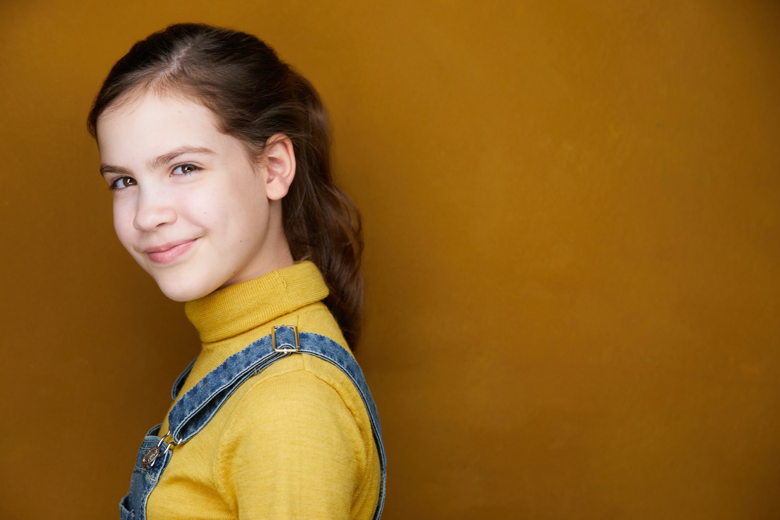 The same session, a mustard turtleneck under denim overalls against mustard