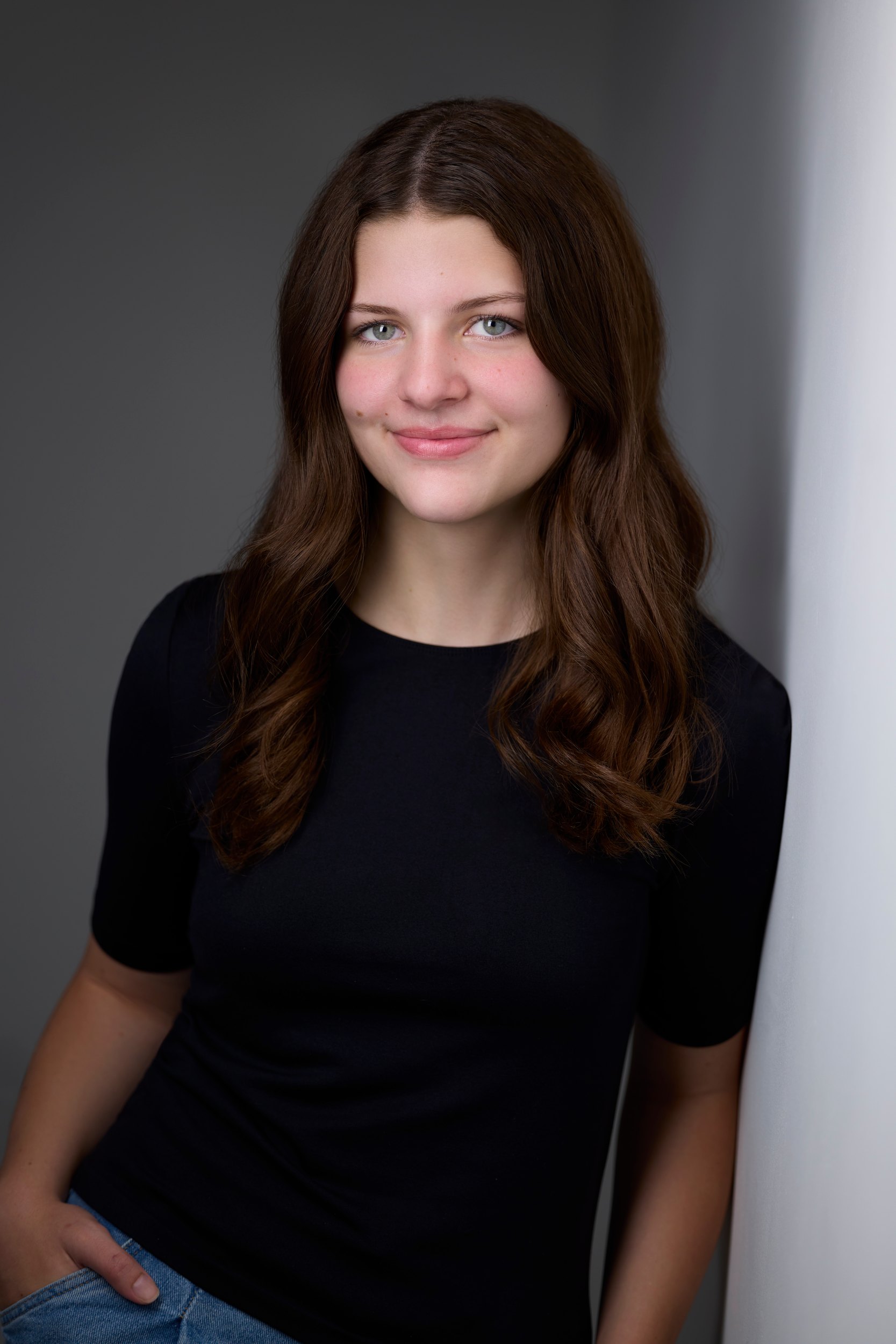 Kids and teens headshot: a black tee against the wall of light, hands in pockets