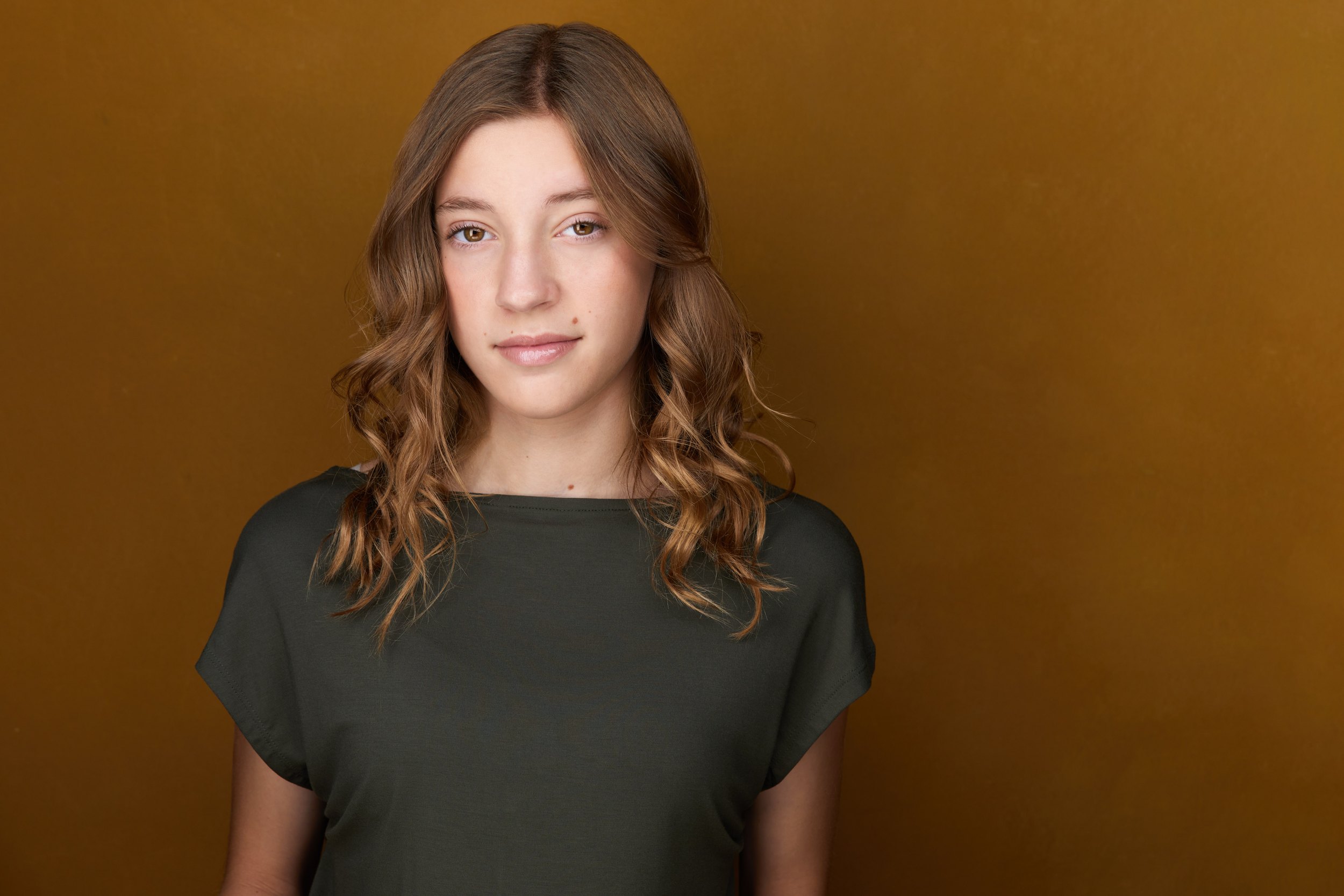Kids and teens headshot: a dark green top against mustard
