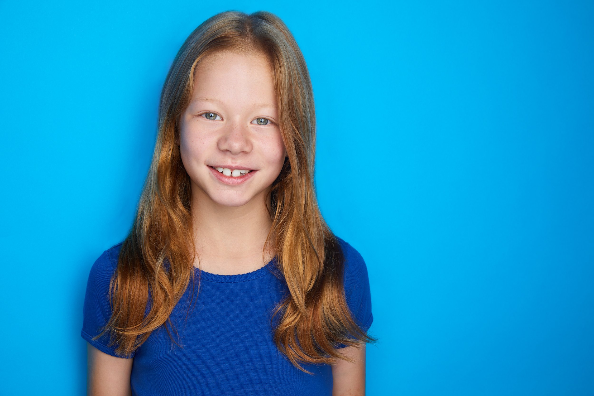 Kids and teens headshot: a blue top against bright blue, red hair
