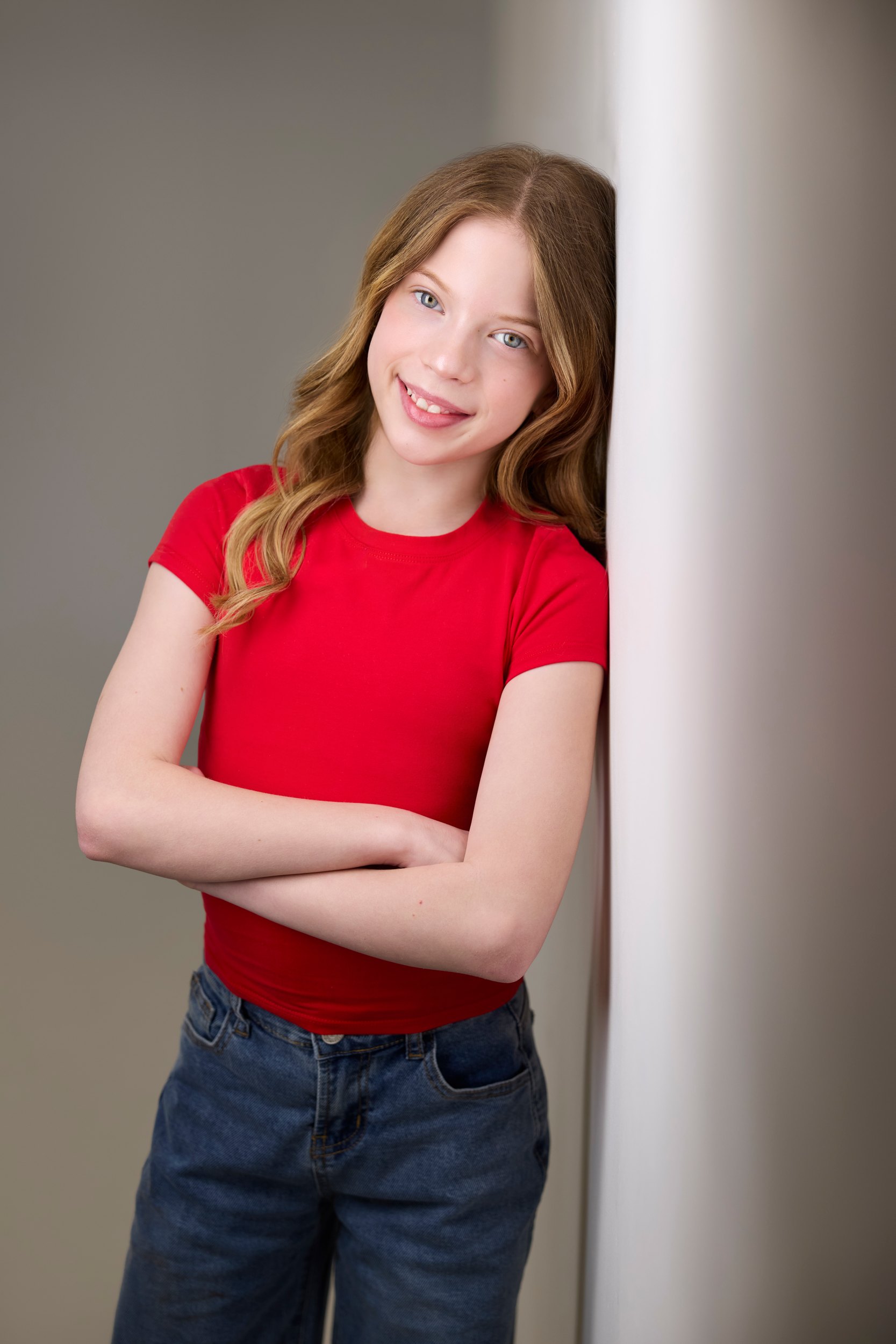 Kids and teens headshot: a red tee against the wall of light, arms crossed