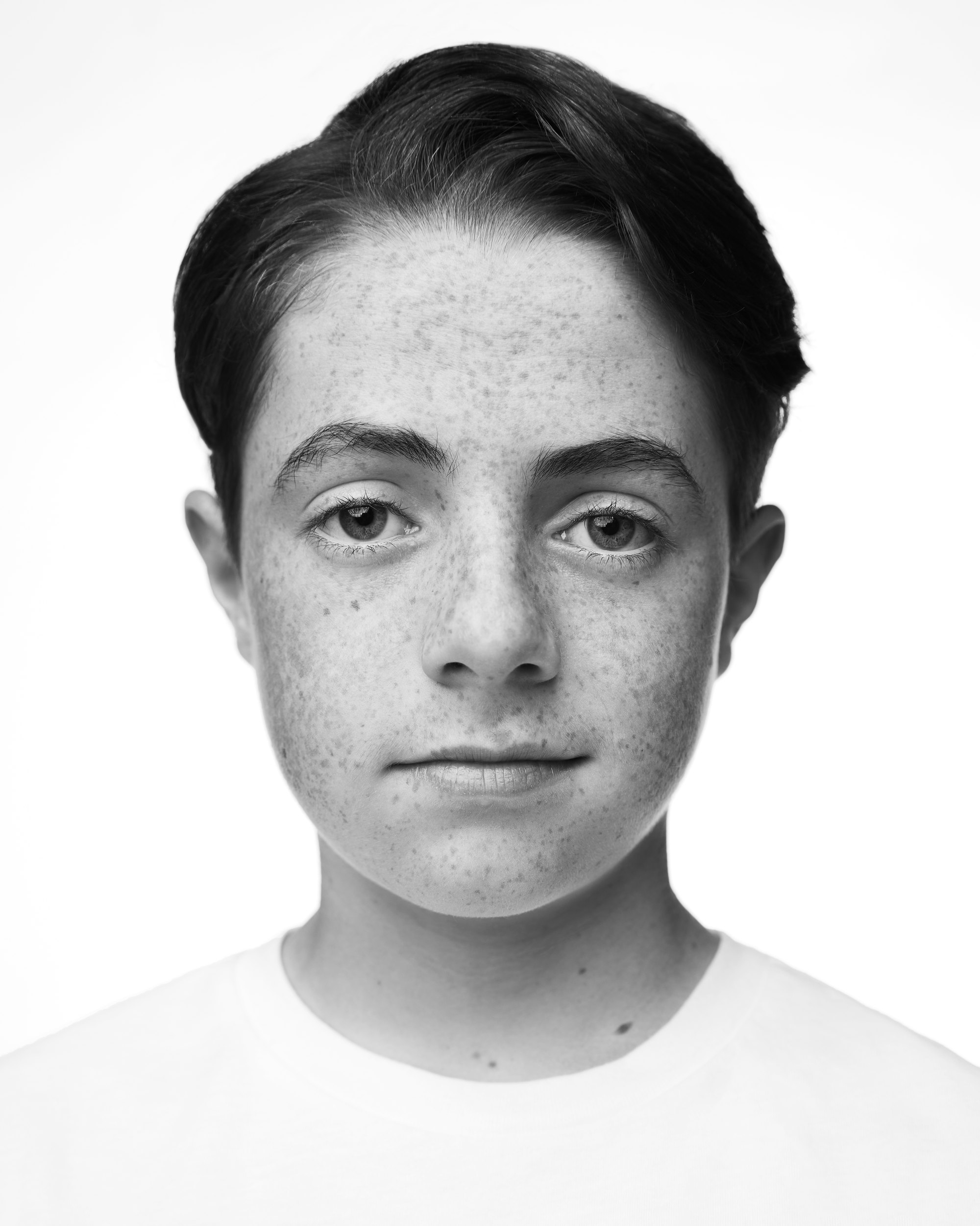Kids and teens headshot in black and white: close, freckles, a white tee against white