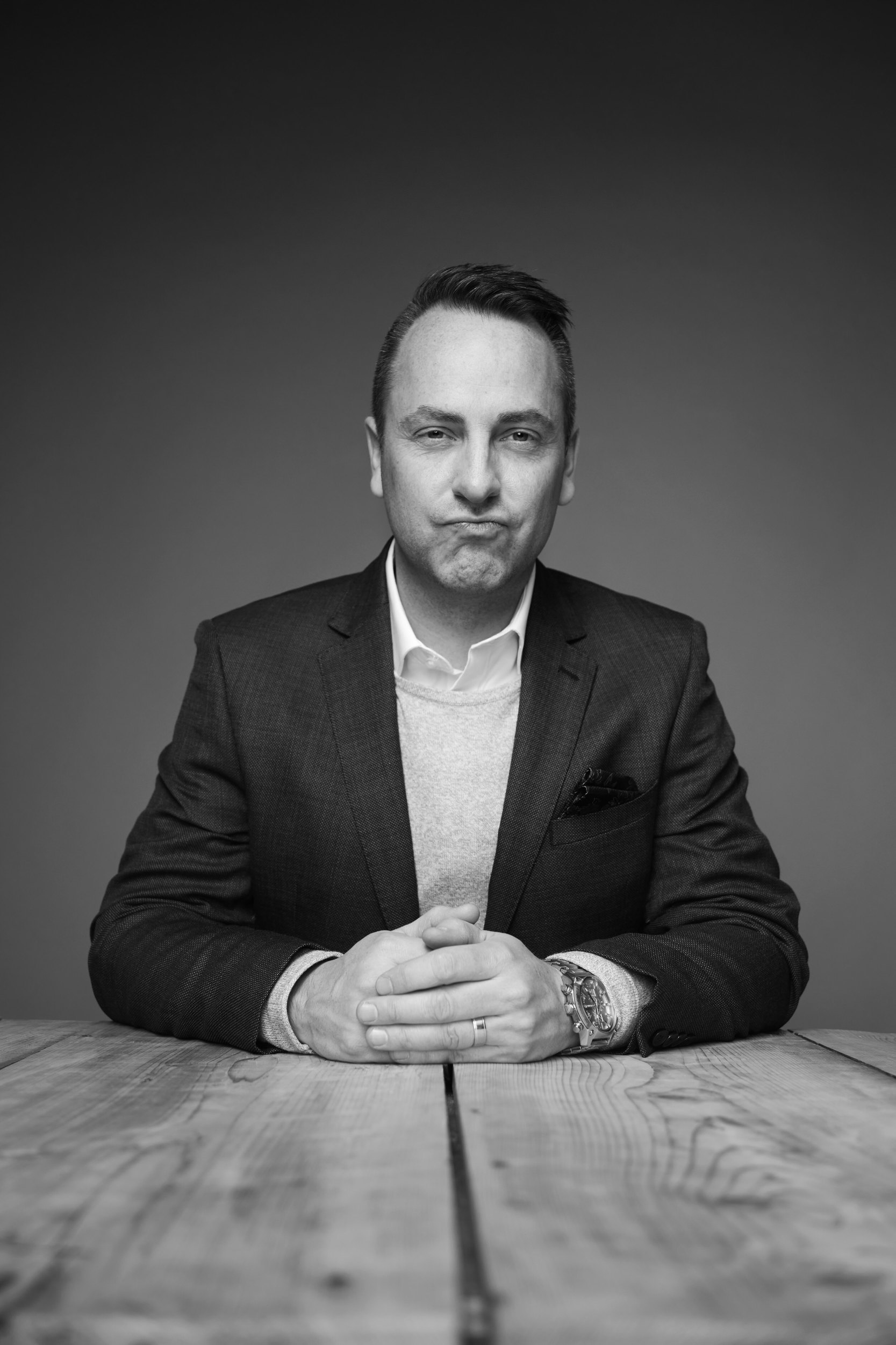 Personal branding portrait in black and white, a grey jacket, at a table