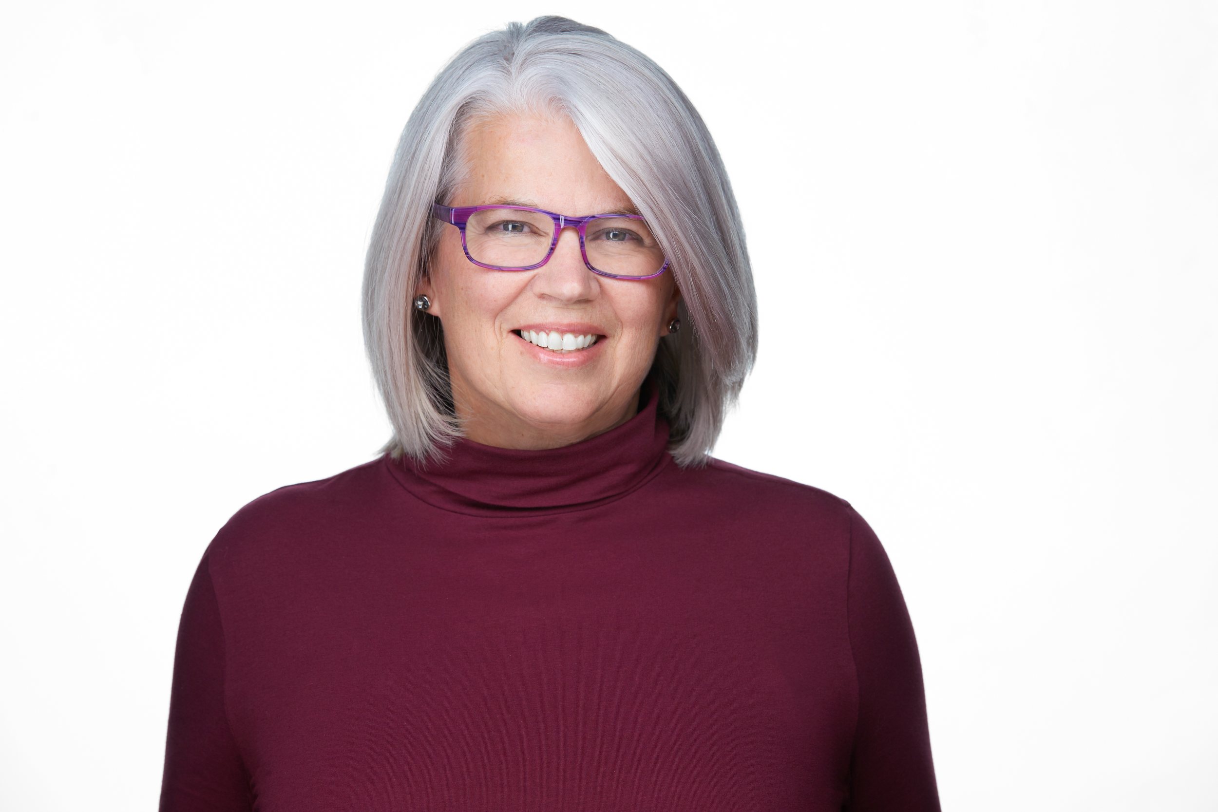 Real estate headshot: silver hair, glasses and a burgundy turtleneck, on white