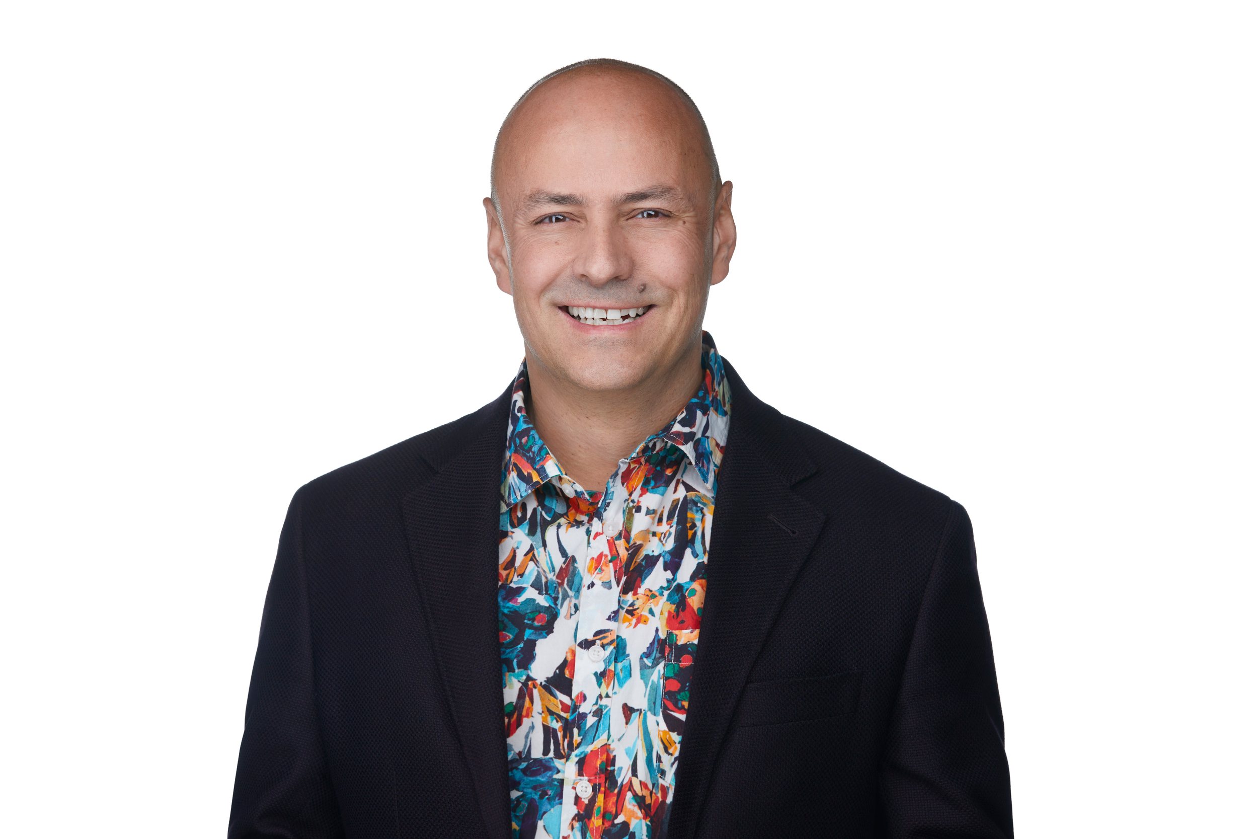 Real estate headshot: a bright floral shirt under a black blazer, laughing, on white