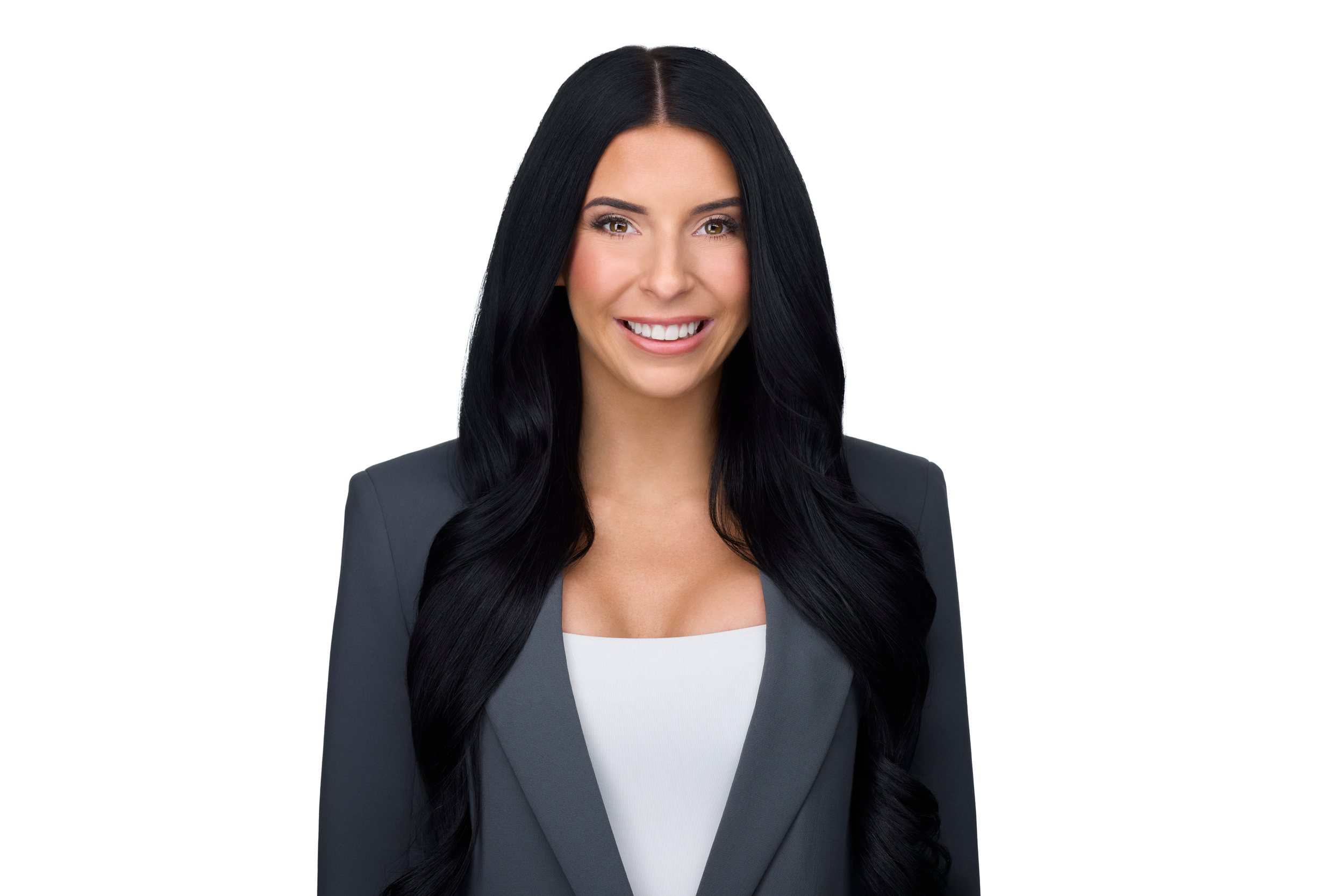 Real estate headshot: long dark hair, a grey blazer over white, on white