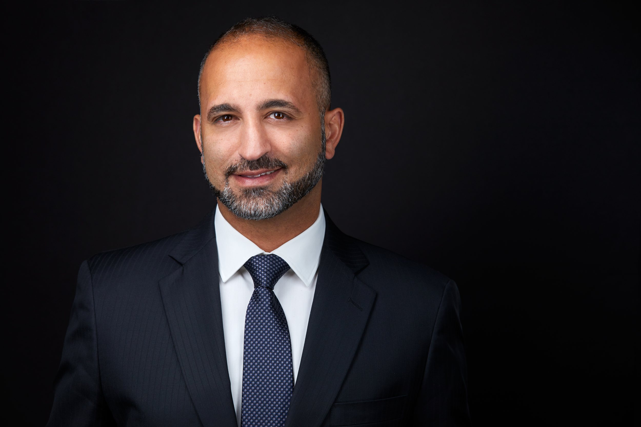Real estate headshot: a trimmed beard, a navy suit and tie, on dark