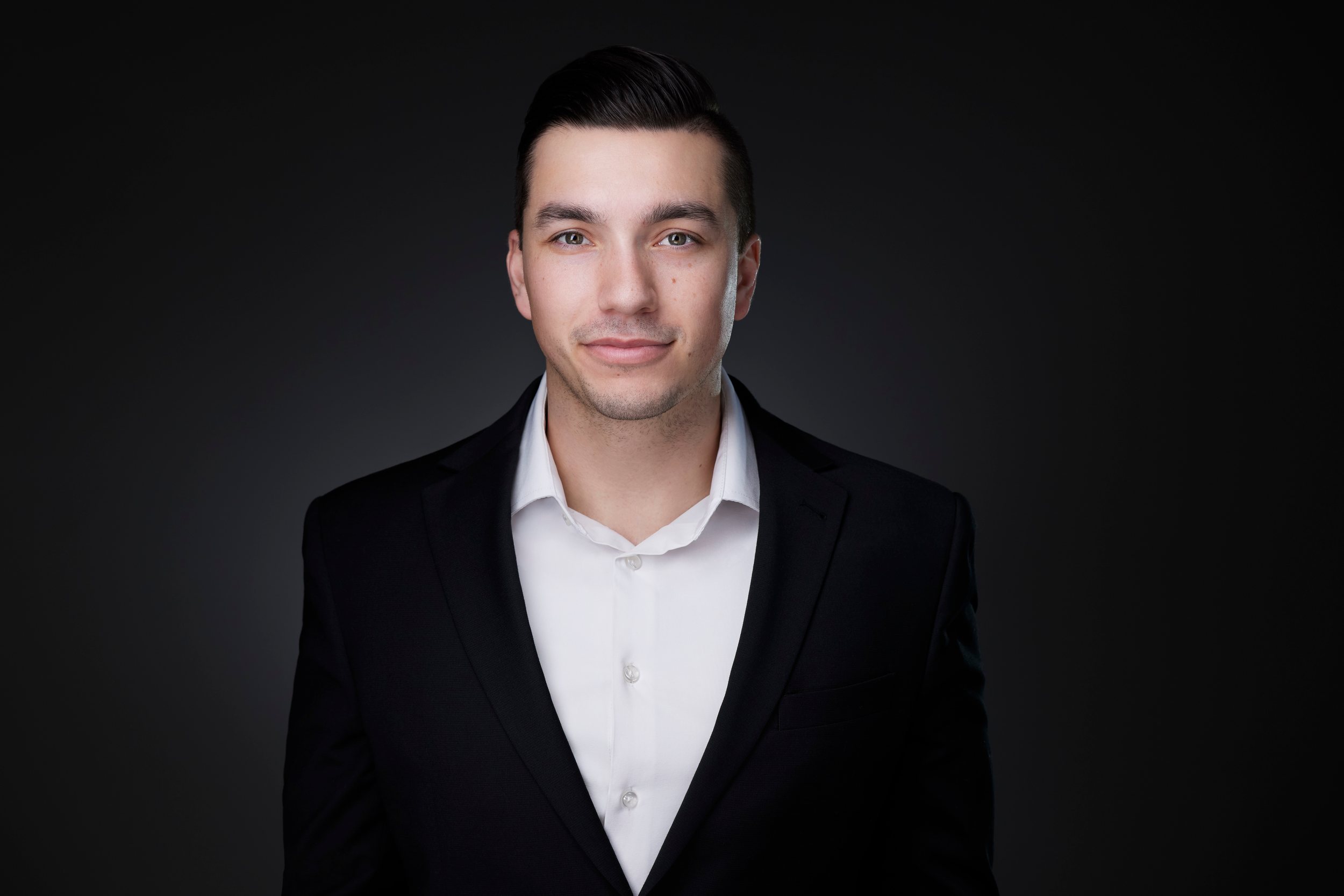 Real estate headshot: a black suit and an open white collar, on dark