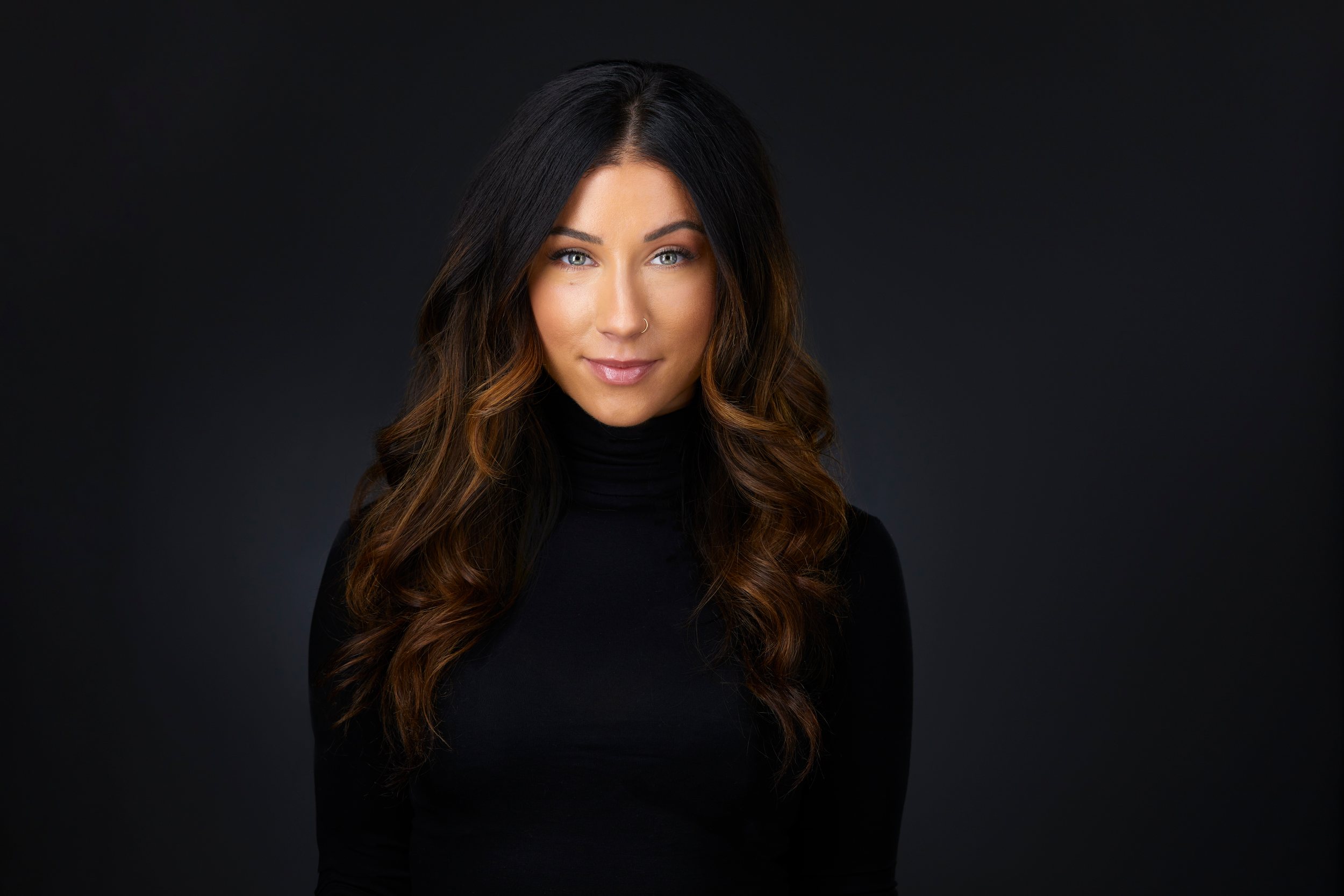 Real estate headshot: long wavy hair and a black turtleneck, on dark