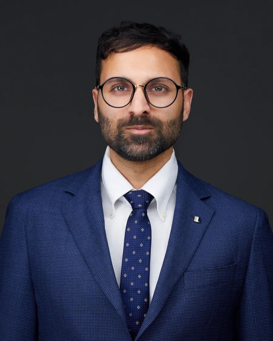 Chivers Carpenter staff headshot, Edmonton: glasses, a navy suit and dotted tie, on charcoal
