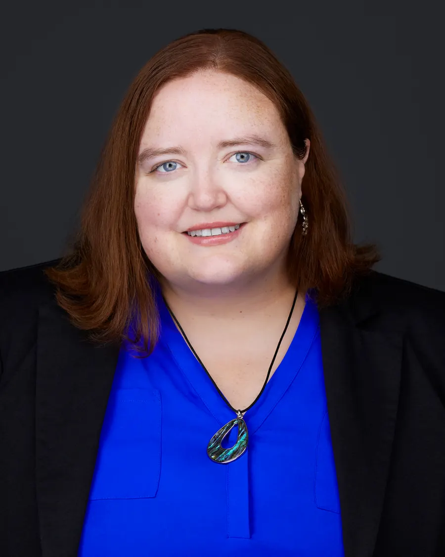Chivers Carpenter staff headshot, Edmonton: a cobalt top under a black blazer, on charcoal