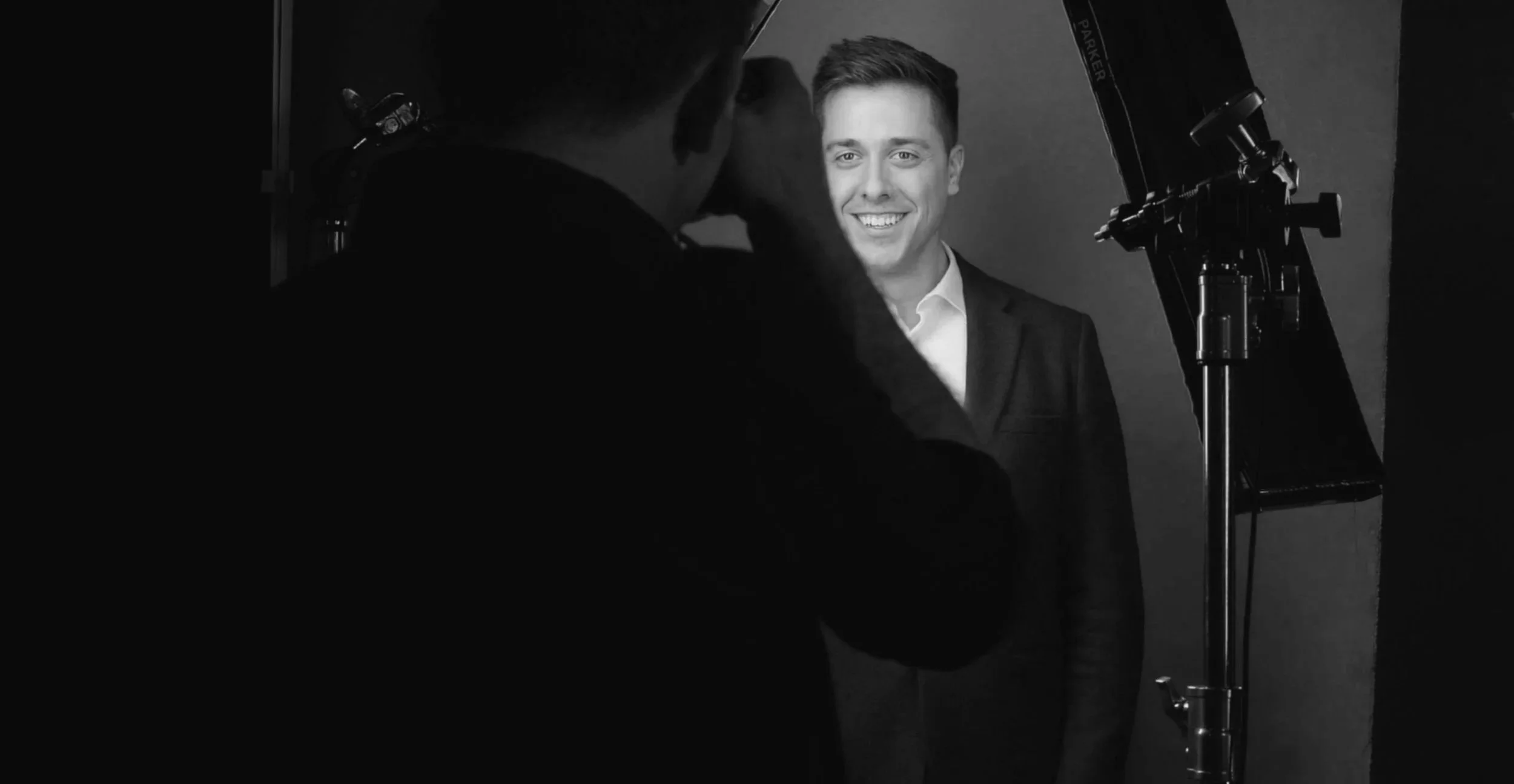 Ryan behind the camera, photographing a man in a suit, the lights either side